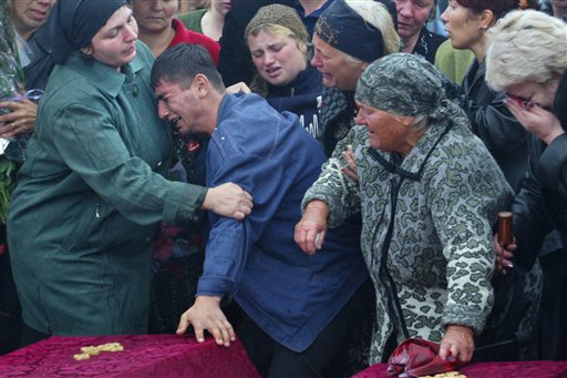 Unidentified Ossetians weep over the coffins of hostages killed in the school siege during a funeral in Beslan, Monday Sept. 6, 2004. (AP)