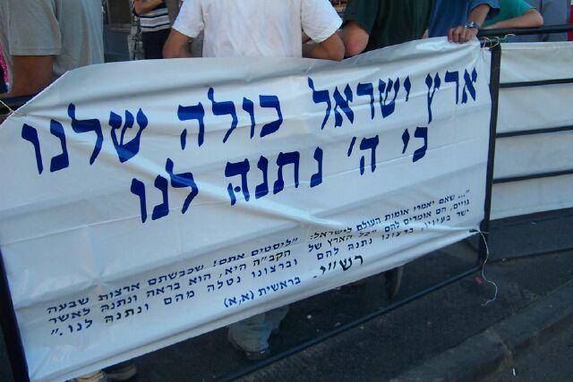 Demonstrators holding a sign in Hebrew reading 'All the land of Israel is ours, because God gave it to us.' (Photo: Jacob Richman)